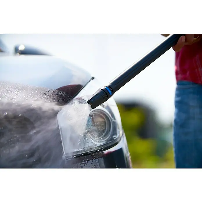 Nilfisk Click & Clean Fahrzeugset - 4 -tlg. - Nahaufnahme eines Autoscheinwerfers, der mit einem Hochdruckreiniger gereinigt wird, wobei der Fokus auf der Reinigung des Scheinwerfers liegt.
