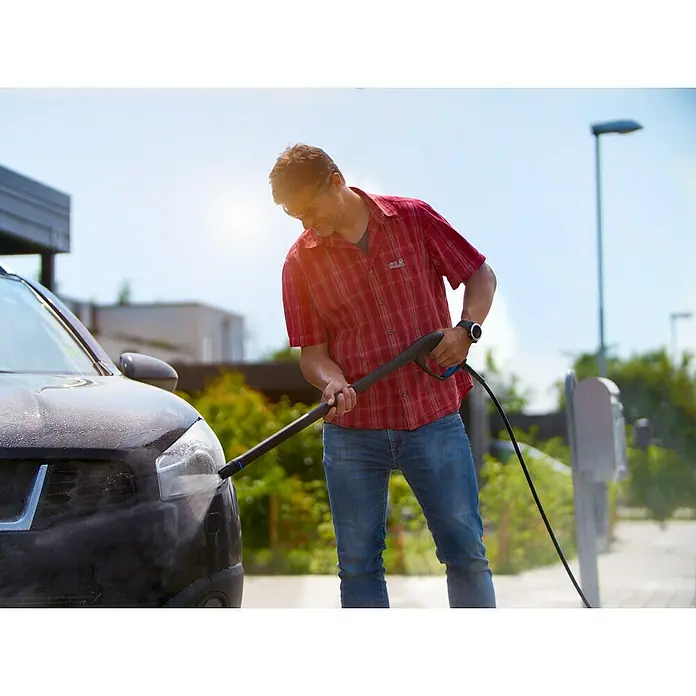 Nilfisk Click & Clean Kit de limpieza de automóviles - 4 pzs. - Hombre lavando el coche con lavadora a presión. Lleva camisa roja y jeans. El coche es negro.
