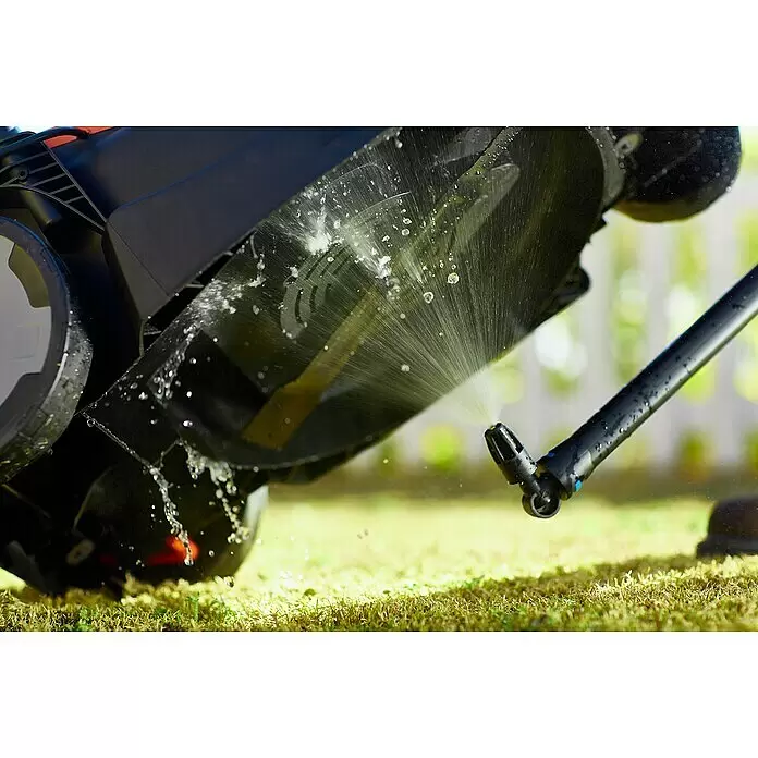 Nilfisk Click & Clean Unterboden-Sprühdüse - Winkel: 90 ° - Unterseite eines schwarzen Rasenmähers wird mit Wasserstrahlen eines Sprühers gereinigt, die auf die Messer spritzen.