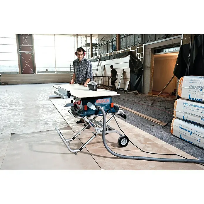 Bosch Professional Werkbank GTA 60 W - Arbeitshöhe: 622 mm, Belastbarkeit: 180 kg - Ein Mann bedient eine Bosch Tischkreissäge mit Absaugung in einer Baustelle, umgeben von Baumaterialien.