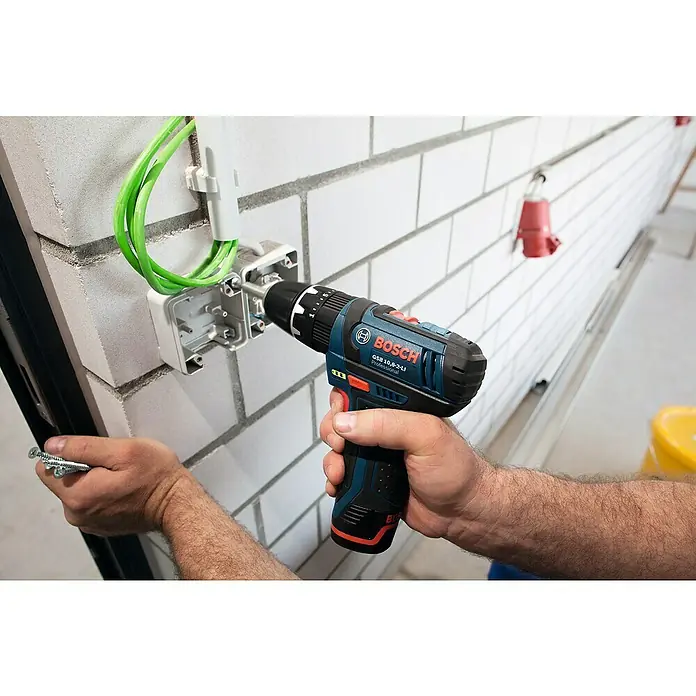 Bosch Professional Akku-Schlagbohrschrauber GSB 12V-15 - 12 V, 2 Akkus, 2 Ah - 4 Ah, 30 Nm, 2 Akkus + Ladegerät + 25-tlg. Bit-Set/14-tlg. Bohrer-Set + Tasche - Ein Arbeiter befestigt eine Wanddose mit einem Bosch Akku-Bohrschrauber, Modell GSB 10,8-2-LI Professional, während er Schrauben hält.
