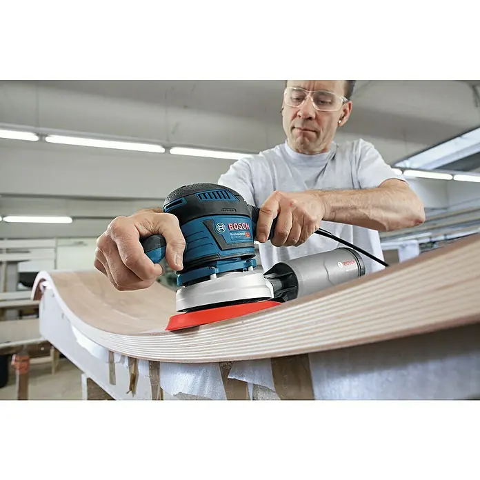 Bosch Professional Elektro-Exzenterschleifer GEX 40-150 - 400 W, Durchmesser Schleifteller: 150 mm - Ein Mann schleift ein Holzstück mit einem blauen Bosch Exzenterschleifer für ein feines Finish. Werkzeuge für Holzbearbeitung.