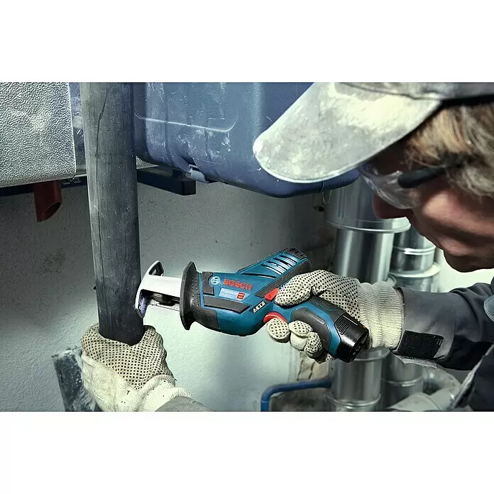 Bosch Professional Akku-Säbelsäge GSA 12V-14 - 12 V, Li-Ionen, 2 Akkus, 3 Ah - Eine Person in Schutzausrüstung verwendet eine blau-schwarze Bosch Säbelsäge zum Schneiden eines schwarzen Rohrs.