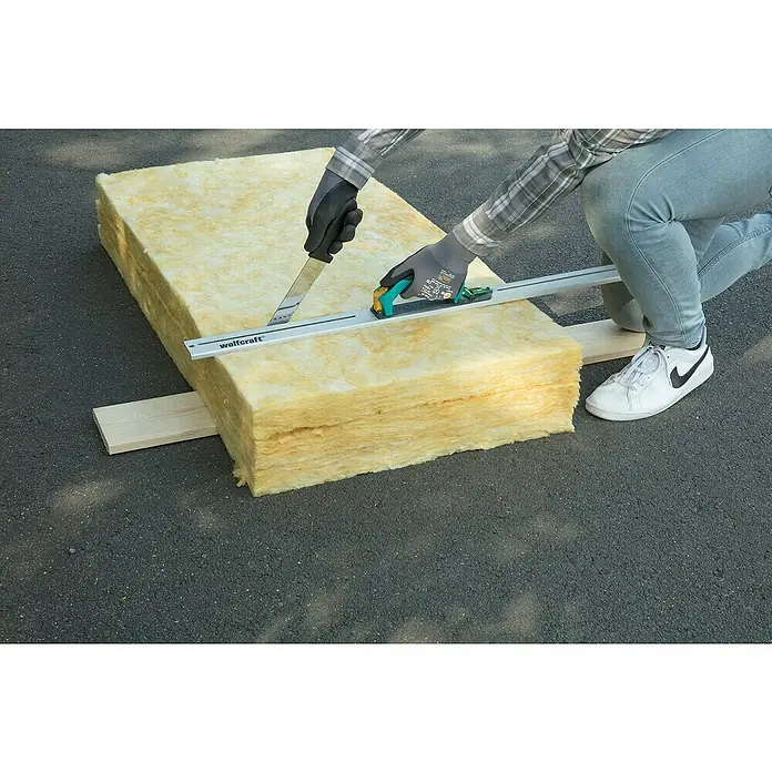 Wolfcraft Dämmstoffmesser - Klingenlänge: 305 mm - Eine Person schneidet mit einem Wolfcraft Dämmstoffschneider Mineralwolle zu, um sie für Isolierungszwecke anzupassen.