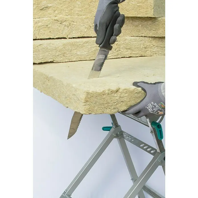 Wolfcraft Dämmstoffmesser - Klingenlänge: 305 mm - Eine Person schneidet Steinwolle mit einem Messer auf einem Arbeitstisch, um sie für Bau- oder Dämmprojekte vorzubereiten.