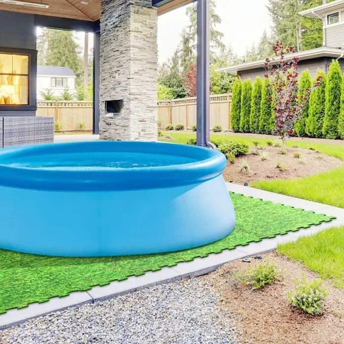 Estera de protección de suelo Puzzle - L x An: 50 x 50 cm, Verde - Una piscina inflable con borde azul se encuentra sobre baldosas de césped verde en el patio trasero.