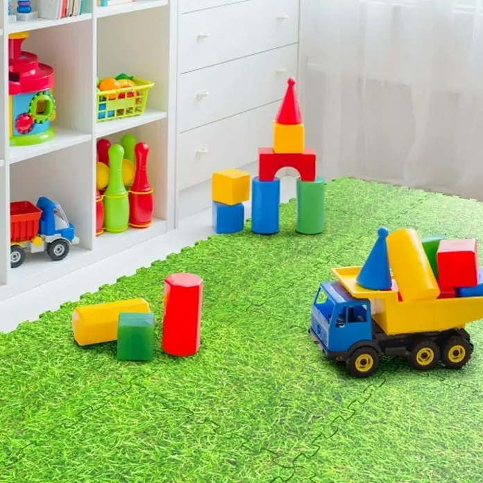 Estera de protección de suelo Puzzle - L x An: 50 x 50 cm, Verde - Escena de una habitación infantil con juguetes como bloques de construcción y un camión de juguete sobre una alfombra verde.