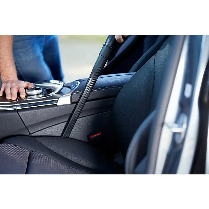 Nilfisk Auto-Set Premium - 4 -tlg. - Innenraumreinigung eines Autos mit Staubsauger, Fokus auf Ledersitz und Mittelkonsole.
