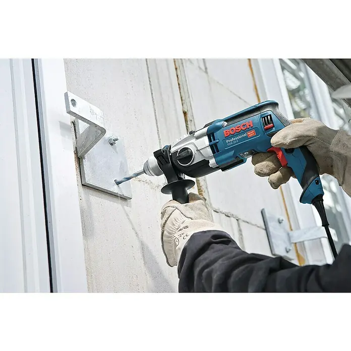 Bosch Professional Schlagbohrmaschine GSB 20-2 - 850 W, Schnellspannbohrfutter - Eine Bosch Professional GSB 20-2 Schlagbohrmaschine wird verwendet, um Löcher in eine Wand zu bohren, wobei die Stabilität durch einen Zusatzgriff gewährleistet wird.