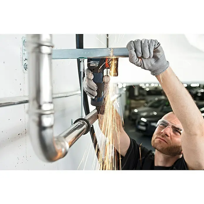 Bosch Professional Akku-Winkelschleifer GWS 12V-76 - 18 V, 2 Akkus, 2 Ah, Durchmesser Scheibe: 76 mm - Ein Mann benutzt einen Winkelschleifer, um Metall zu schneiden, wobei Funken fliegen. Er trägt Schutzbrille und Handschuhe.