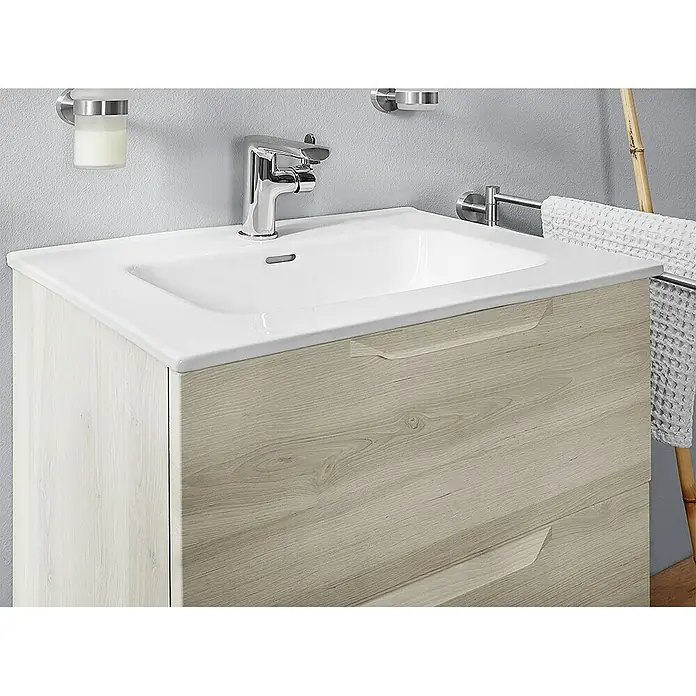 Riva Urban Waschtischunterschrank - 60 x 45 x 56,5 cm - Nahaufnahme eines Waschbeckens mit Unterschrank in Holzoptik, Armatur und Handtuchhalter. Das Badmöbel bietet Stauraum und ist modern gestaltet.