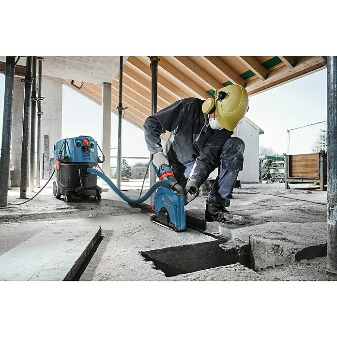 Bosch Professional Elektro-Nass- & Trockensauger GAS 35 H AFC - 1.200 W, 35 l - Ein Bauarbeiter benutzt einen Bosch Mauernutfräse mit angeschlossenem Staubsauger, um präzise Schnitte in den Betonboden zu machen.