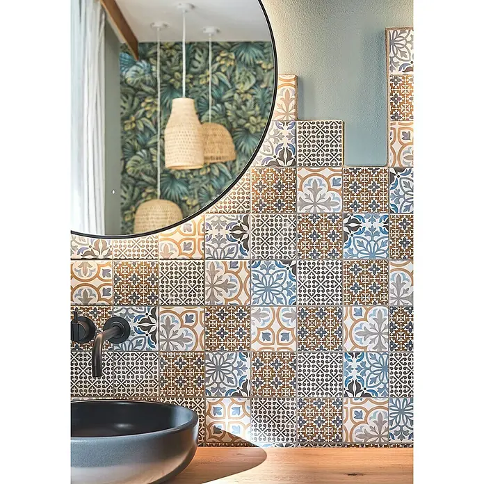 Mosaikfliese Quadrat Classico Mix Porto - 29,8 x 29,8 cm, Mehrfarbig, Matt - Detailansicht eines Badezimmers mit einer Wand aus farbenfrohen Zementfliesen, einem schwarzen, runden Spiegel und einem Waschbecken.