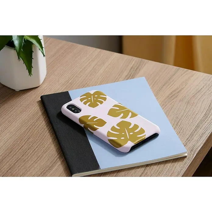 Cricut Joy Vinylfolie Smart Vinyl Ablösbar - Gold, 121,9 x 13,9 cm, Wieder entfernbar - Nahaufnahme eines Smartphones mit einer trendigen Handyhülle mit Monstera-Blatt-Design auf einem Notizbuch, neben einer Pflanze.