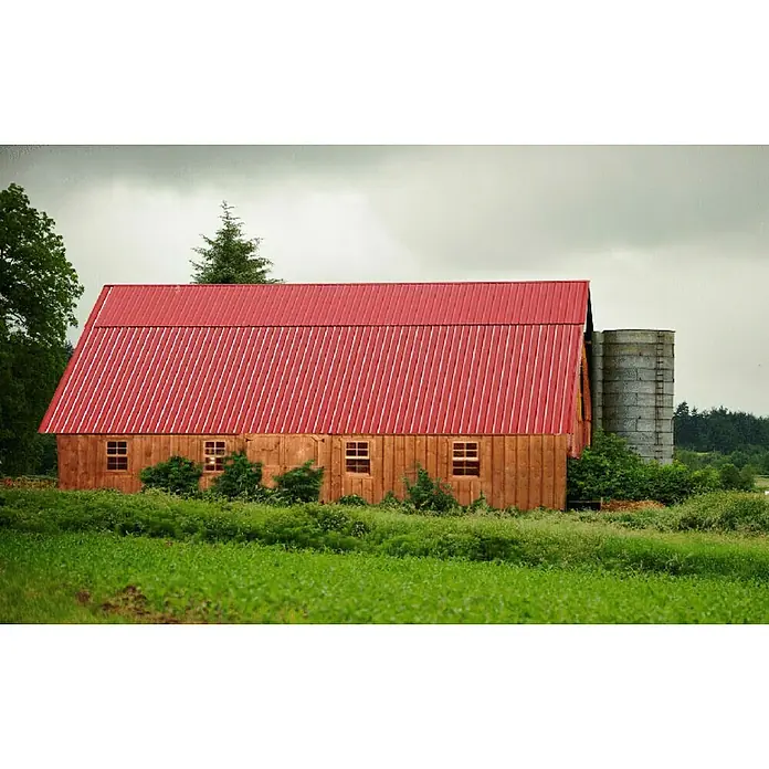 Metdach Dachblech Schwallblech200 x 90,5 x 0,4 cm, Rot - Rote Scheune mit Silo in ländlicher Umgebung. Das Gebäude ist hellbraun mit einem roten Dach, umgeben von viel Grün.
