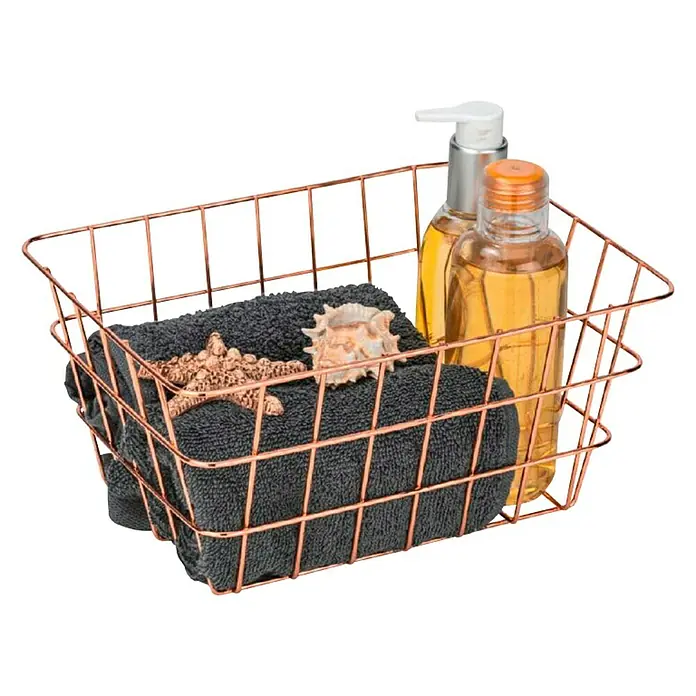 Wenko Cesta para el baño Viana - L x An x Al: 12 x 18 x 25 cm, Metal, Cobre - Cesta de alambre con toalla, estrella de mar, concha y dos botellas. La cesta es de alambre de cobre y se encuentra delante de un fondo negro.