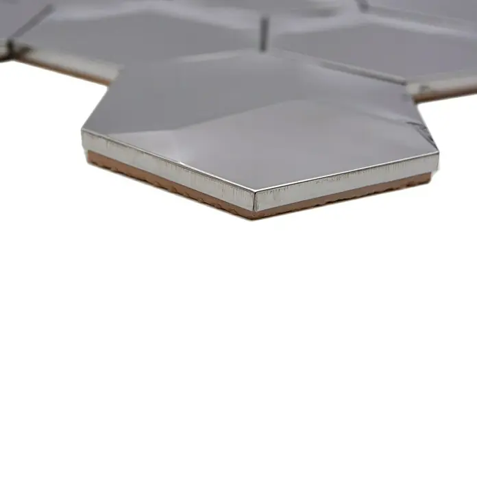 Mosaikfliese Hexagon HXM 10SG - 26,2 x 23 cm, Silber, Glänzend - Nahaufnahme von sechseckigen, silbernen Fliesen mit brauner Unterseite. Die Metallfliesen schimmern und reflektieren das Licht.