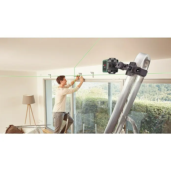 Bosch Kreuzlinienlaser Quigo Green II - Max. Arbeitsbereich: 12 m - Ein Mann befestigt eine Halterung mit einem Kreuzlinienlaser von Bosch, der an einer Leiter befestigt ist. Das grüne Laserlicht ist gut sichtbar.