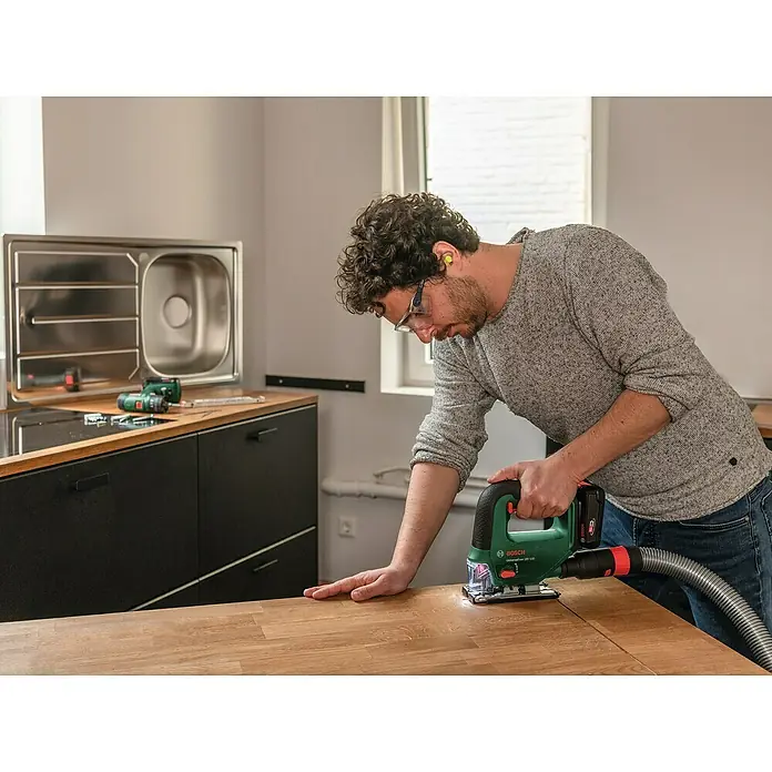 Bosch Power for All 18V Akku-Stichsäge UniversalSaw 18V-100 - 18 V, Ohne Akku, Leerlaufhubzahl: 2.600 /min - Mann arbeitet mit einer Bosch Universalsäge 18V-100 Akku-Stichsäge an einem Holztisch, um ein Projekt zu verwirklichen.