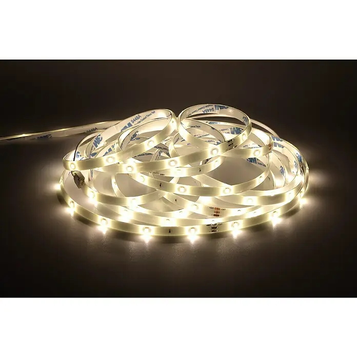 Tween Light Tira LED - Largo: 10 m, Color de luz: Blanco cálido, 13 W - Primer plano de una tira de luces LED blanco cálido con adhesivo sobre una superficie oscura, ideal para iluminación ambiental.
