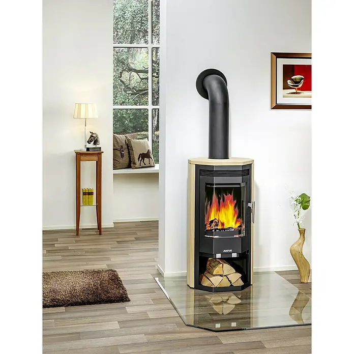 Justus Kaminofen Usedom 5 II - 5,5 kW, Raumheizvermögen: 88 m³, Material Verkleidung: Sandstein, Sandstein/Schwarz - Ein Justus Kaminofen mit Holzscheiten und Flammenspiel, platziert auf einer Glasplatte in einem modernen Wohnzimmer.