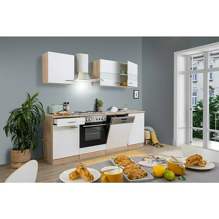 Respekta Singleküche Merle Typ 1 - Breite: 220 cm, Weiß, Mit Elektrogeräten, Volumen Backofen: 60 l - Eine moderne Küchenzeile mit weißen Fronten und hellen Holzdetails, ergänzt durch Elektrogeräte und einen gedeckten Tisch mit Gebäck.