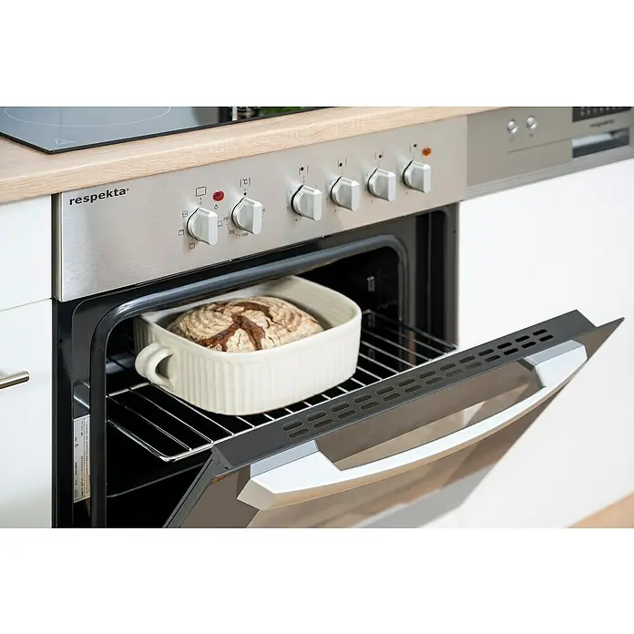 Respekta Singleküche Merle Typ 2 - Breite: 270 cm, Weiß, Mit Elektrogeräten - Ein Respekta-Backofen mit einem Brot in einer Schüssel. Der Backofen steht auf einer Küchentheke mit Herdplatten darüber.
