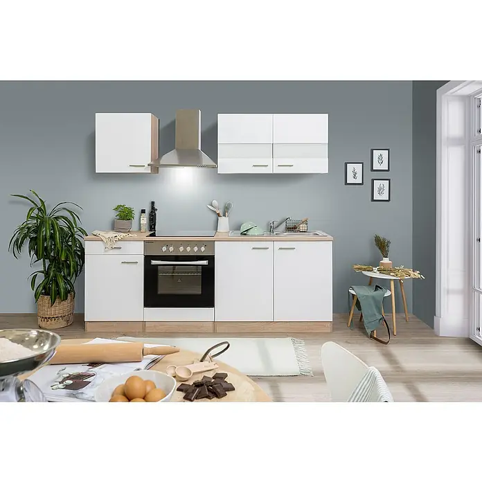 Respekta Singleküche Merle Typ 2 - Breite: 210 cm, Weiß, Mit Elektrogeräten, Volumen Backofen: 72 l - Moderne Küche mit weißen Schränken, Edelstahl-Dunstabzugshaube und vorbereiteten Zutaten zum Backen auf dem Tisch.