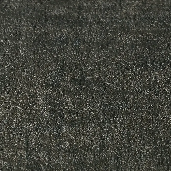 Rasch Factory 4 Vliestapete - Schwarz, Uni, 10,05 x 0,53 m - Nahaufnahme einer Textur mit rauer, dunkler Oberfläche, die an Asphalt oder groben Putz erinnert. Ideal für industrielle Hintergründe.