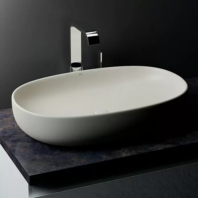 RAK Ceramics Feeling Ablaufventil - 1 ¼″, Weiß, Mit Druckknopf - Ovales, helles Aufsatzwaschbecken mit texturierter Oberfläche, kombiniert mit einem modernen Chromhahn auf dunkler Arbeitsplatte.