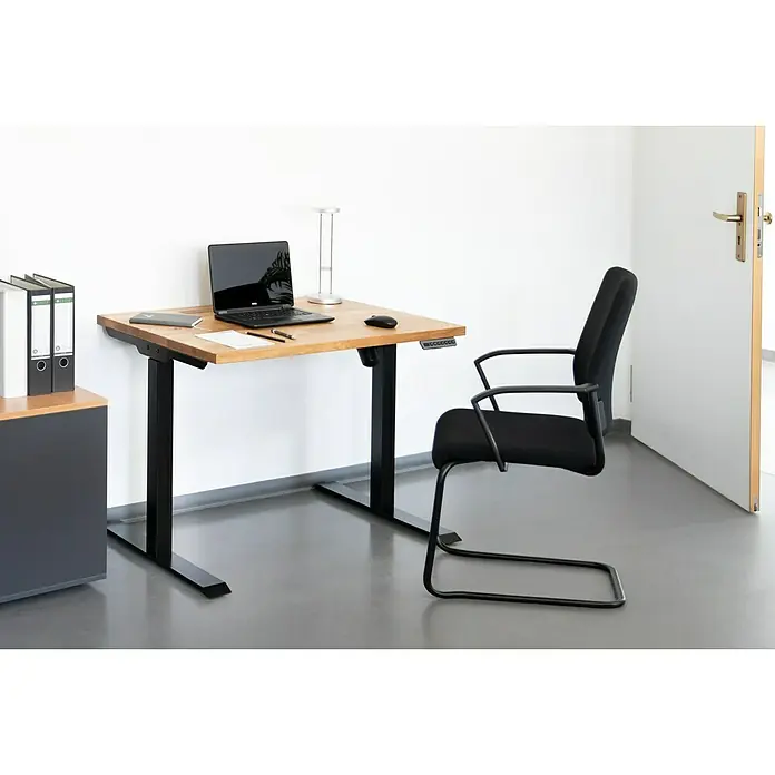 Tischplatte - Eiche, 120 x 80 x 2,6 cm - Ein höhenverstellbarer Schreibtisch mit Laptop, Büromaterial und einer Lampe in einem modernen Büro. Der Schreibtisch ist aus hellem Holz gefertigt.