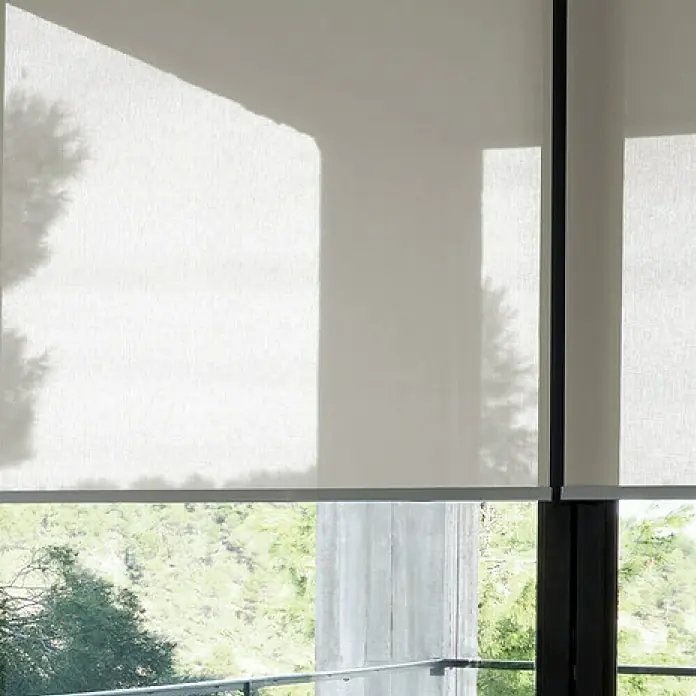 Estor enrollable screen 10% - An x Al: 135 x 190 cm, Blanco lino - Un estor enrollable de filtrado de luz cuelga frente a una ventana, proporcionando privacidad sin oscurecer completamente la habitación.