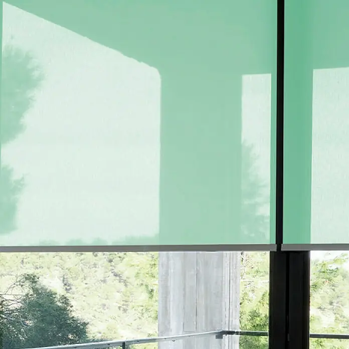 Estor enrollable screen 5% - An x Al: 90 x 250 cm, Verde Mint - Primer plano de dos persianas enrollables de color verde menta, bajadas parcialmente, difuminando una luz natural tenue en la habitación.