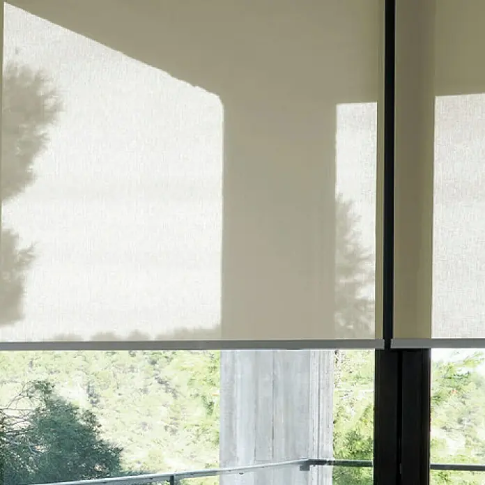 Estor enrollable screen 10% - An x Al: 105 x 250 cm, Lino - Primer plano de persianas enrollables blancas frente a una ventana con vistas a un jardín con muchos árboles. Las persianas enrollables son opacas y dan sombra.