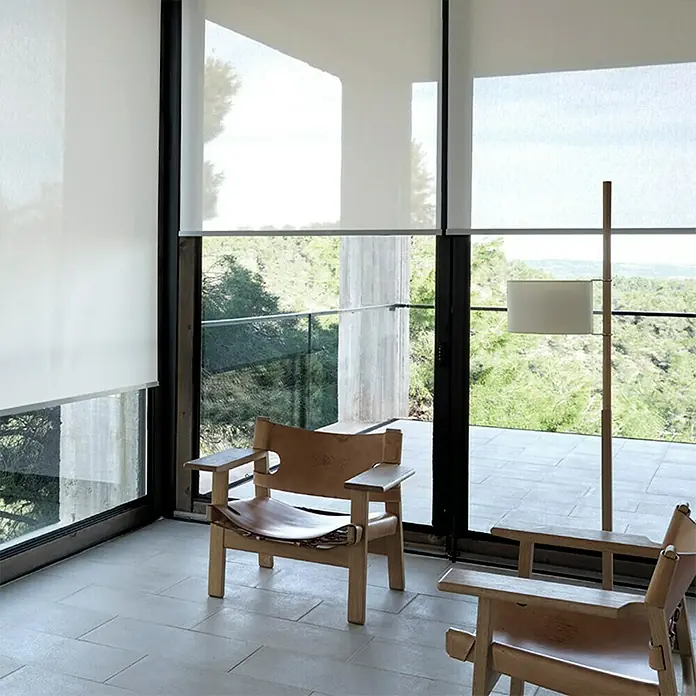 Estor enrollable screen 10% - An x Al: 200 x 250 cm, Blanco - Esta imagen muestra estores enrollables minimalistas en grandes ventanas, creando una habitación luminosa con vistas a la naturaleza.