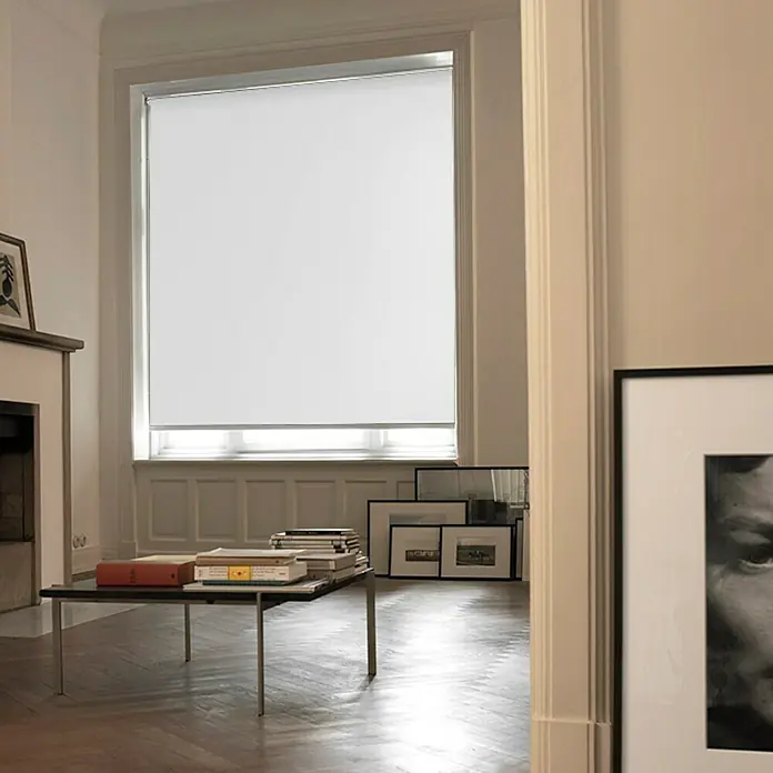 Estor enrollable opaco NDC - An x Al: 200 x 250 cm, Blanco - Un estor enrollable cubre una gran ventana en una sala de estar. El estor es blanco y está situado detrás de una mesa de café con libros.