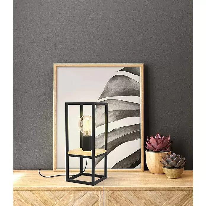 Eglo Libertad Deko-Tischleuchte LIBERTAD - L x B x H: 14 x 14 x 35 cm - Tischleuchte aus schwarzem Metall und hellem Holz auf einem Schrank neben einem gerahmten Bild und Sukkulenten.