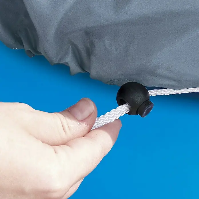 Pool-Abdeckplane Summer WavesDurchmesser: 549 cm, Kunststoff - Detailaufnahme einer Hand, die an einem Zugband mit Stopper einer Poolabdeckung zieht, um diese zu sichern.