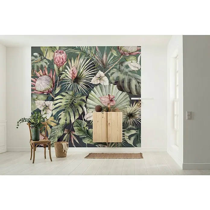 Komar Ink Fototapete Monsterawelt - 6 -tlg., B x H: 300 x 280 cm, Vlies - Wandbild mit tropischen Blumen und Blättern in einem hellen Raum mit Holzschrank und Stuhl, das eine natürliche Atmosphäre schafft.