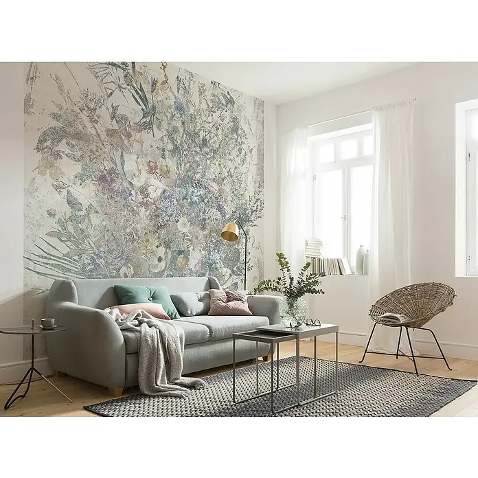 Komar Raw Fototapete Bouquet Blowout - 3 -tlg., B x H: 300 x 280 cm, Vlies - Wohnzimmer mit grauer Couch und floraler Wandtapete. Die Couch ist mit Kissen und einer Decke dekoriert, die den Raum gemütlich machen.