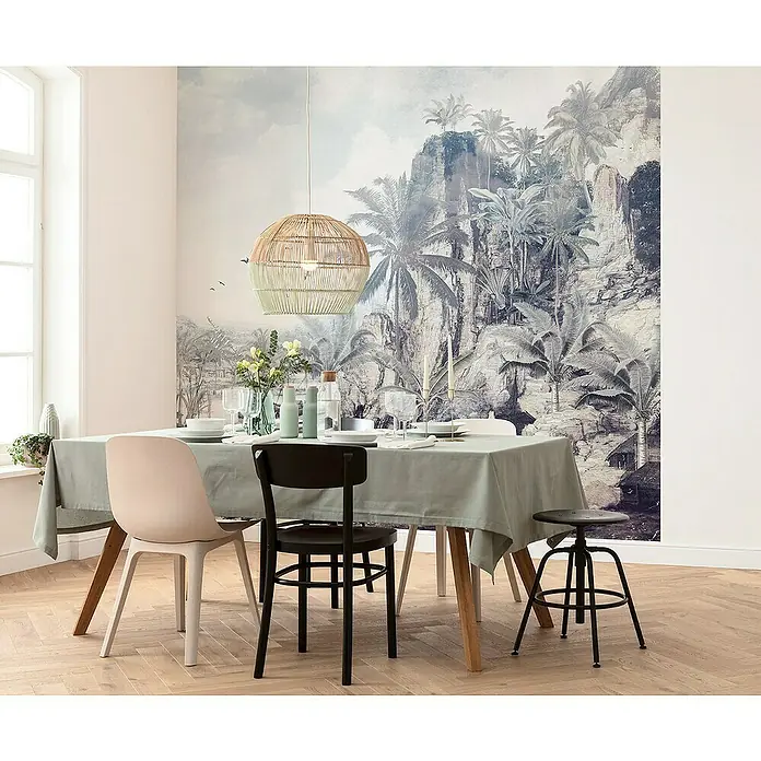 Komar Raw Fototapete Dreamworld3 -tlg., B x H: 300 x 280 cm, Vlies - Ein Esstisch mit einem grünen Tischtuch, Stühlen und einer dekorativen Hängelampe im Raum mit einer tropischen Wandmalerei.