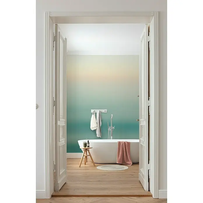 Komar Ink Fototapete Ocean Sense - 8 -tlg., B x H: 400 x 280 cm, Vlies - Das Badezimmer verfügt über eine freistehende Badewanne, einen hölzernen Beistelltisch und eine beruhigende, farbverlaufene Wand, die durch eine offene Tür zu sehen ist.