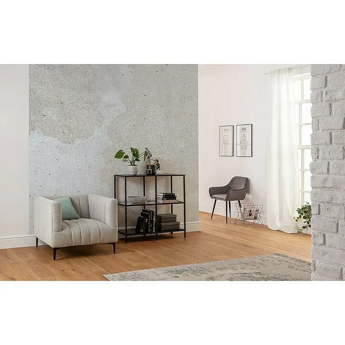 Komar Raw Fototapete Puro - 3 -tlg., B x H: 300 x 280 cm, Vlies - Ein gemütliches Wohnzimmer mit einem hellgrauen Sessel, einem schwarzen Regal und Dekorationen auf einem Holzboden. Elegante Deko sorgt für Wohlfühlatmosphäre.