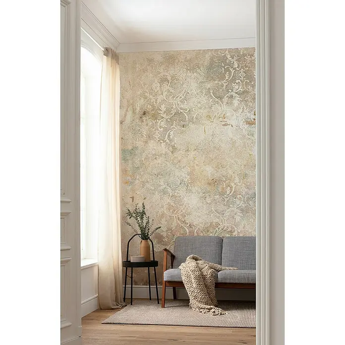Komar Raw Fototapete Ancient Times - 2 -tlg., B x H: 200 x 280 cm, Vlies - Elegantes Wohnzimmer mit einer grauen Couch, einem kleinen Beistelltisch mit einer Vase und einer gemusterten Wandtapete.