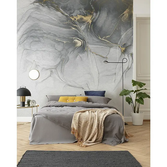 Komar Raw Fototapete Ink Gold Fluid - 6 -tlg., B x H: 300 x 280 cm, Vlies - Schlafzimmer mit grauem Bett, gelbem Kissen und gemusterter Wand.