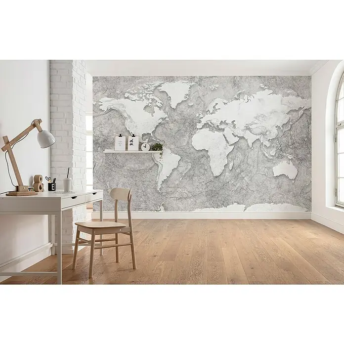 Komar Home Fototapete World Relief - 7 -tlg., B x H: 350 x 250 cm, Vlies - Ein Arbeitszimmer mit einer Weltkarte an der Wand, einem weißen Schreibtisch und einem Holzstuhl, das eine ruhige und inspirierende Atmosphäre schafft.