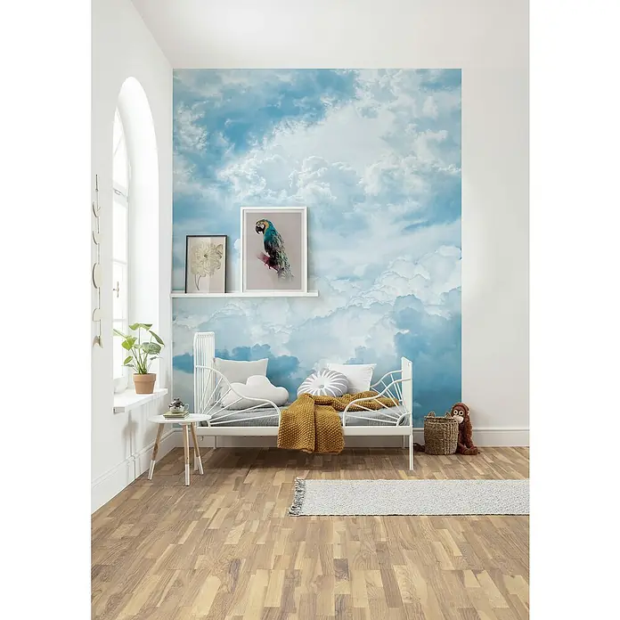 Komar Home Fototapete Himmelszelt - 4 -tlg., B x H: 200 x 250 cm, Vlies - Ein Kinderzimmer mit einem weißen Bett, dekoriert mit einer Wolkendecke und Bildern an der Wand, für eine ruhige Atmosphäre.