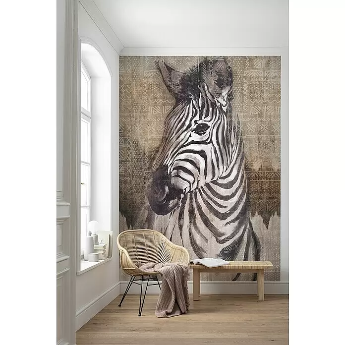 Komar Home Fototapete Zebra - 4 -tlg., B x H: 200 x 250 cm, Vlies - Wandtapete mit Zebragesicht und Stammesmuster im Hintergrund, die einen Raum mit Rattanstuhl und Holzbank dekoriert.