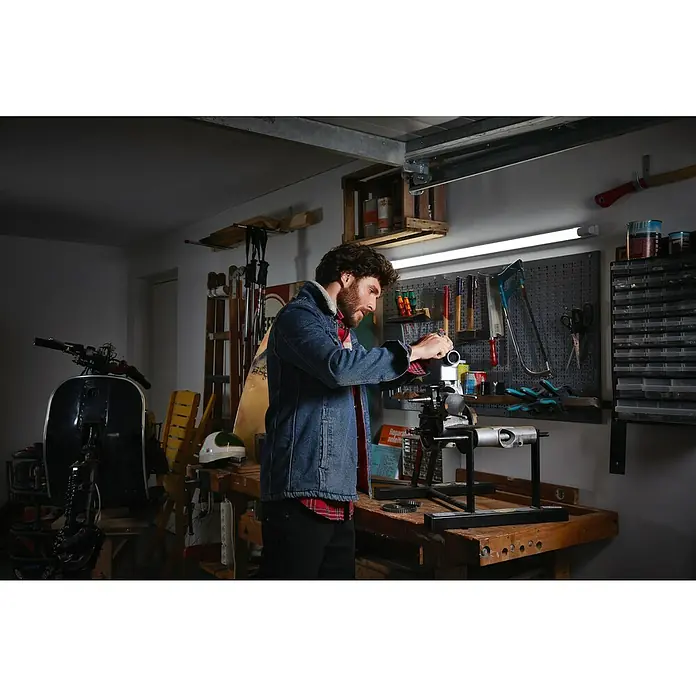 Osram LED-Lichtleiste Power Batten - L x B x H: 120 x 8,2 x 4,8 cm, Lichtfarbe: Kaltweiß, 50 W, 220 V - 240 V - Ein Mann arbeitet in seiner Werkstatt an einem Maschinenteil, das auf einer Werkbank steht. Über der Werkbank hängt eine Werkzeugwand.