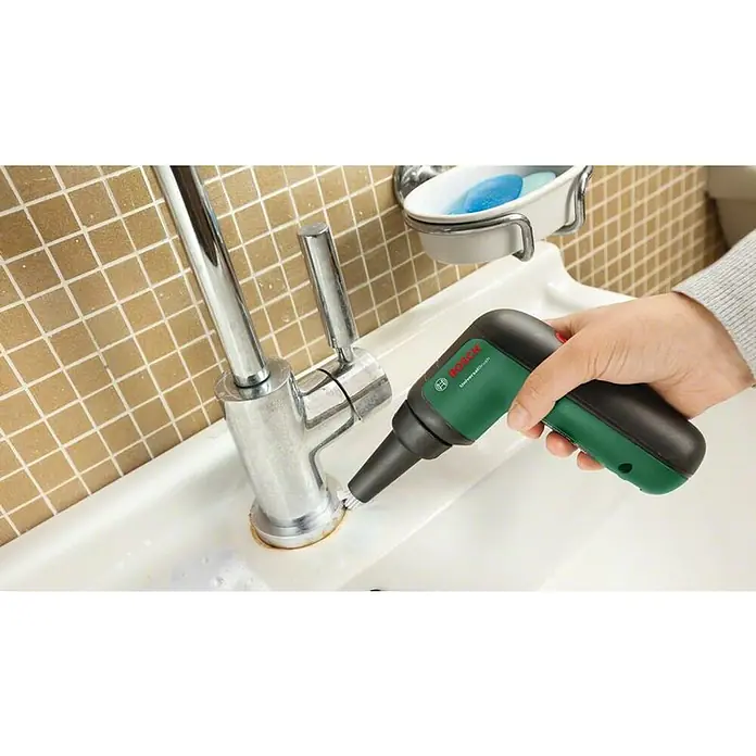 Bosch Akku-Reinigungsbürste UniversalBrush - 7 -tlg., 3,6 V, 1,5 Ah - Ein Mann reinigt einen Wasserhahn mit einer grünen Bosch Universalbürste, um hartnäckigen Schmutz zu entfernen. Effektive Reinigung im Bad.